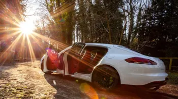 Rear side view of Porsche Panamera with both rear and passenger doors open showing its burdungy interior