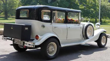 Rear side view of vintage Beauford with black roof, black picnic trunk mounted at the rear of the vehicle and spare wheel mounted on the side skirt of the vehicle.