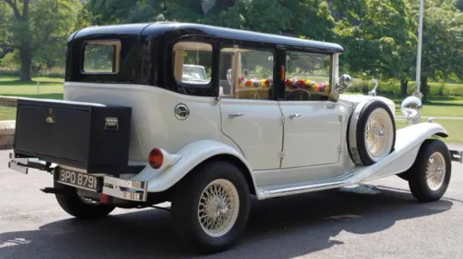 Rear side view of vintage Beauford with black roof, black picnic trunk mounted at the rear of the vehicle and spare wheel mounted on the side skirt of the vehicle.