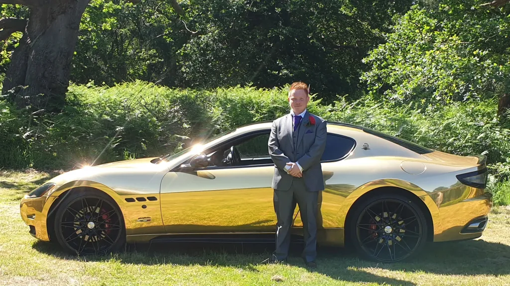 Maserati GranTurismo 'S' with groom standing in front of the vehicle in a green grass field