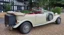 rear right side view of vintage style Beauford Convertible with convertible roof open and black rear picnic trunk