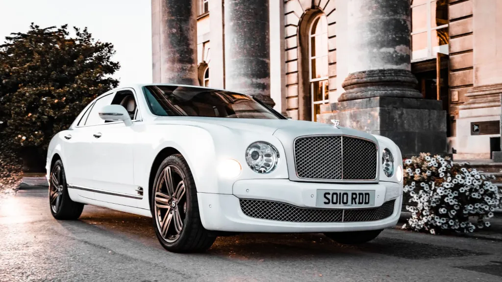 White Bentley Mulsanne with brushed silver bonnet parked in front of a wedding venue