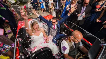 Ford Mustang Convertible wavbing to their wedding guests from inside the Mustang with roof down