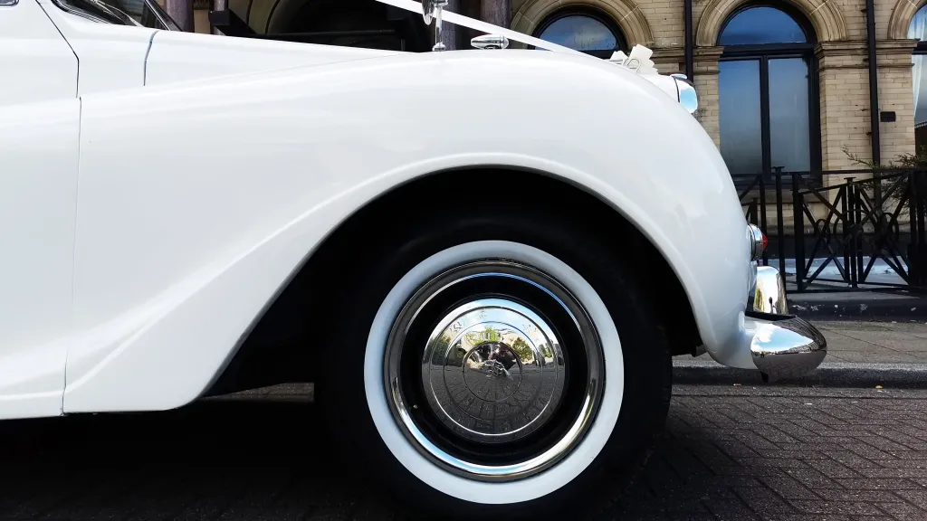 close up view of chrome wheel cap with thin white wall tires on an Austin Princess,