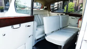 rear interior cabin photo showing white leather seats and additional casual seats raised up for extra seating