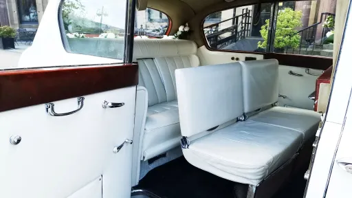 rear interior cabin photo showing white leather seats and additional casual seats raised up for extra seating