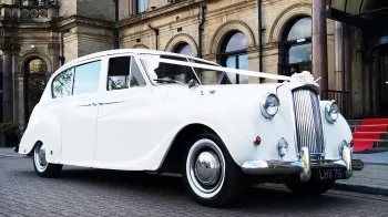 Front right side view of classic austin Princess decorated with white ribbons accross its bonnet, chrome wheels and thin white wall tires