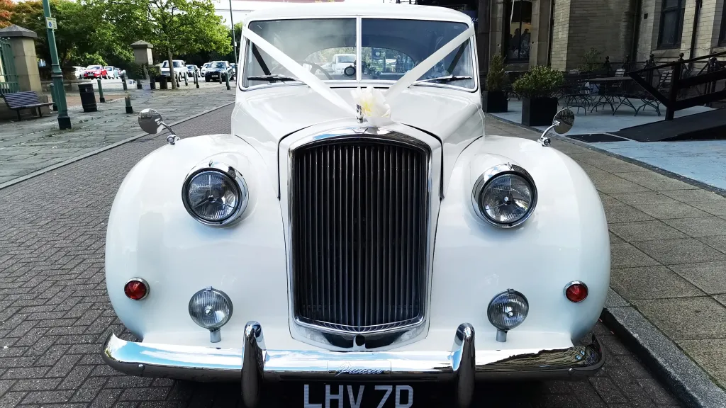 Full front view of classic Austin wedding car dressed with ribbons showing the large chrome radiotor grill at the front
