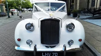 Full front view of classic Austin wedding car dressed with ribbons showing the large chrome radiotor grill at the front