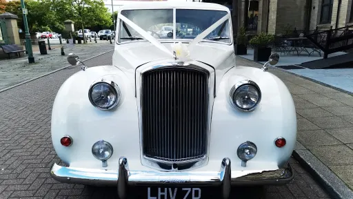 Full front view of classic Austin wedding car dressed with ribbons showing the large chrome radiotor grill at the front