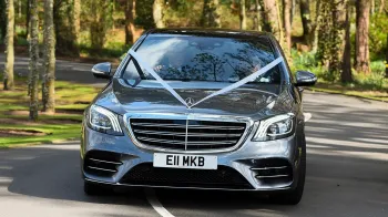 Full front view of a Grey Mercedes decorated with white ribbons