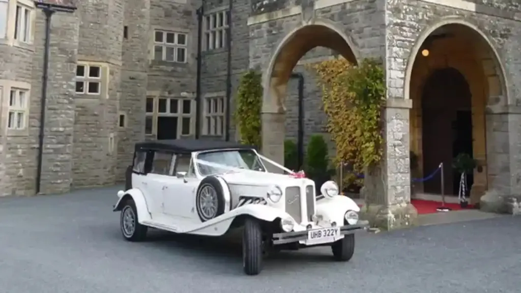 Ivory Beauford Convertible with white ribbons parked in front of wedding venue