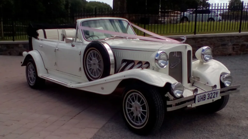 Ivory 30's style vintage Beauford  with light pink ribbons accross its bonnet.