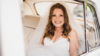 Bride smiling inside the white Rolls-Royce Silver Cloud I