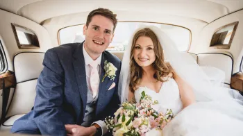 Bride and Groom holding hands and smiling inside a Classic Rolls-Royce Silver Cloud.