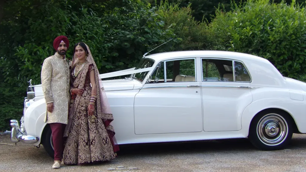 Asian couple standing in front of the white silver cloud car