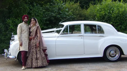 Asian couple standing in front of the white silver cloud car