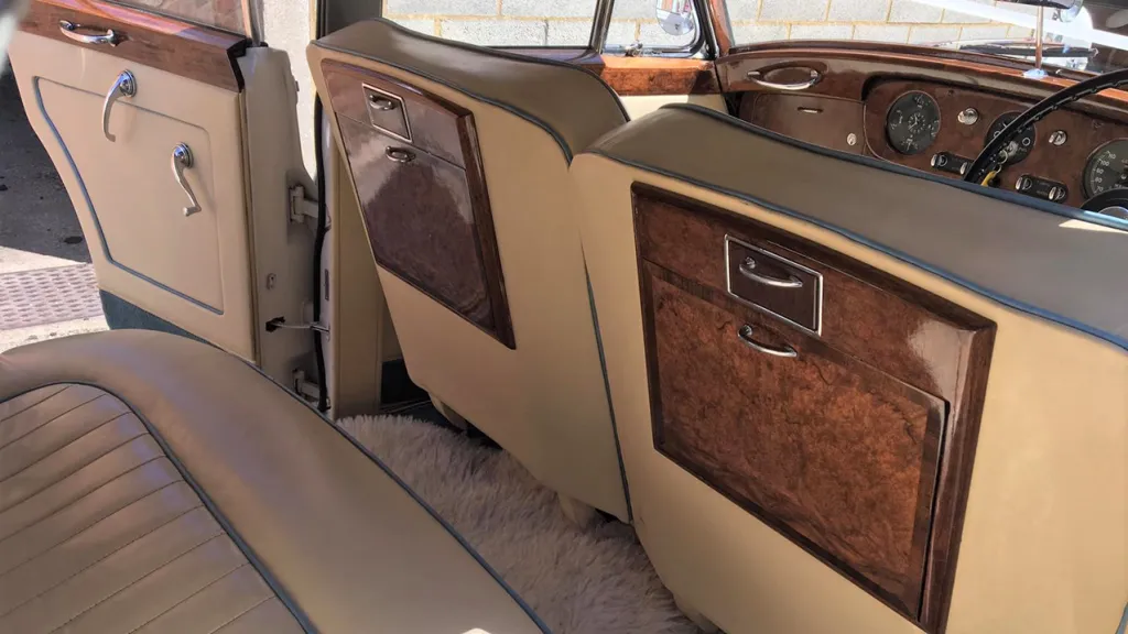 Rear seat of the classic rolls-royce with cream leather interior and blue pipping
