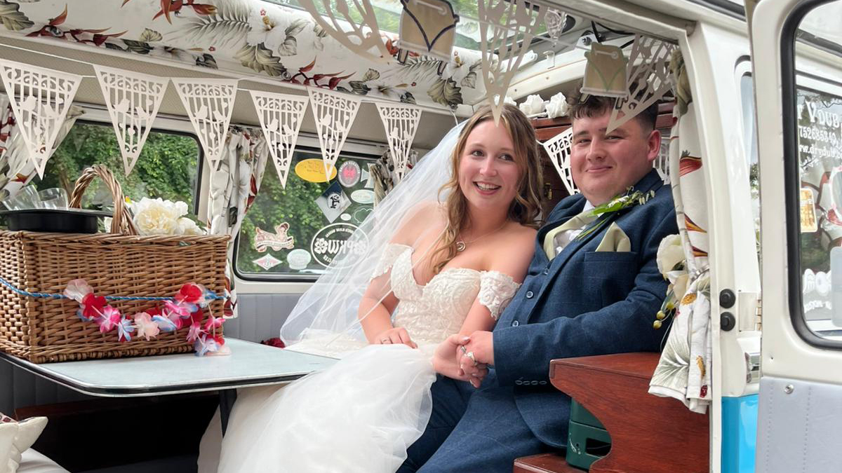 Bride and Groom seating inside a classic VW Campervan decorated with wedding decoration